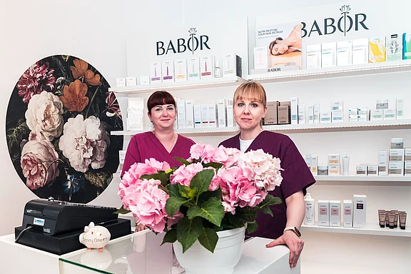 Mitarbeiterinnen des Kosmetikstudios vor einem Produktregal mit Pflegeprodukten